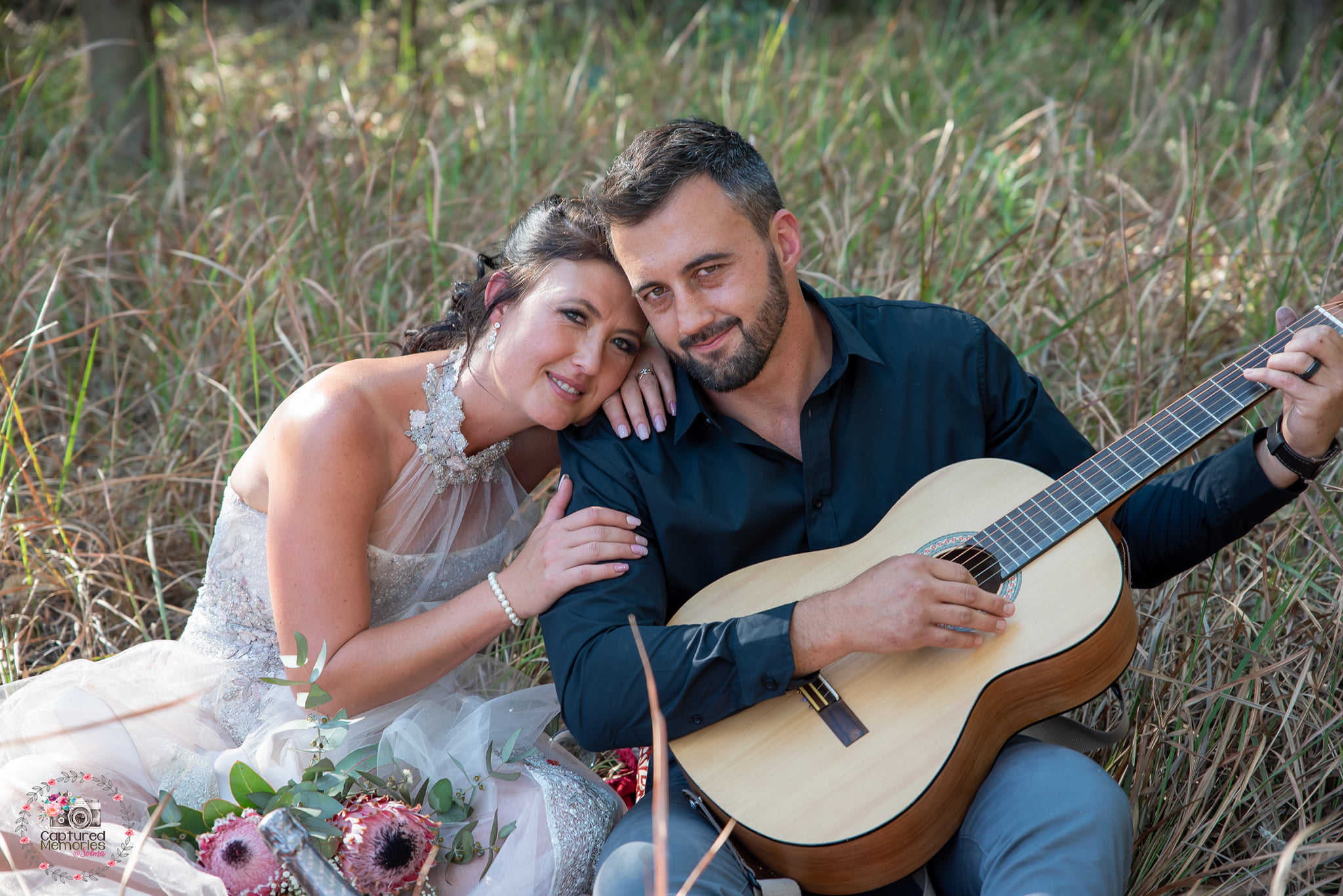 Wedding couple sitting together with an acoustic guitar among reeds.