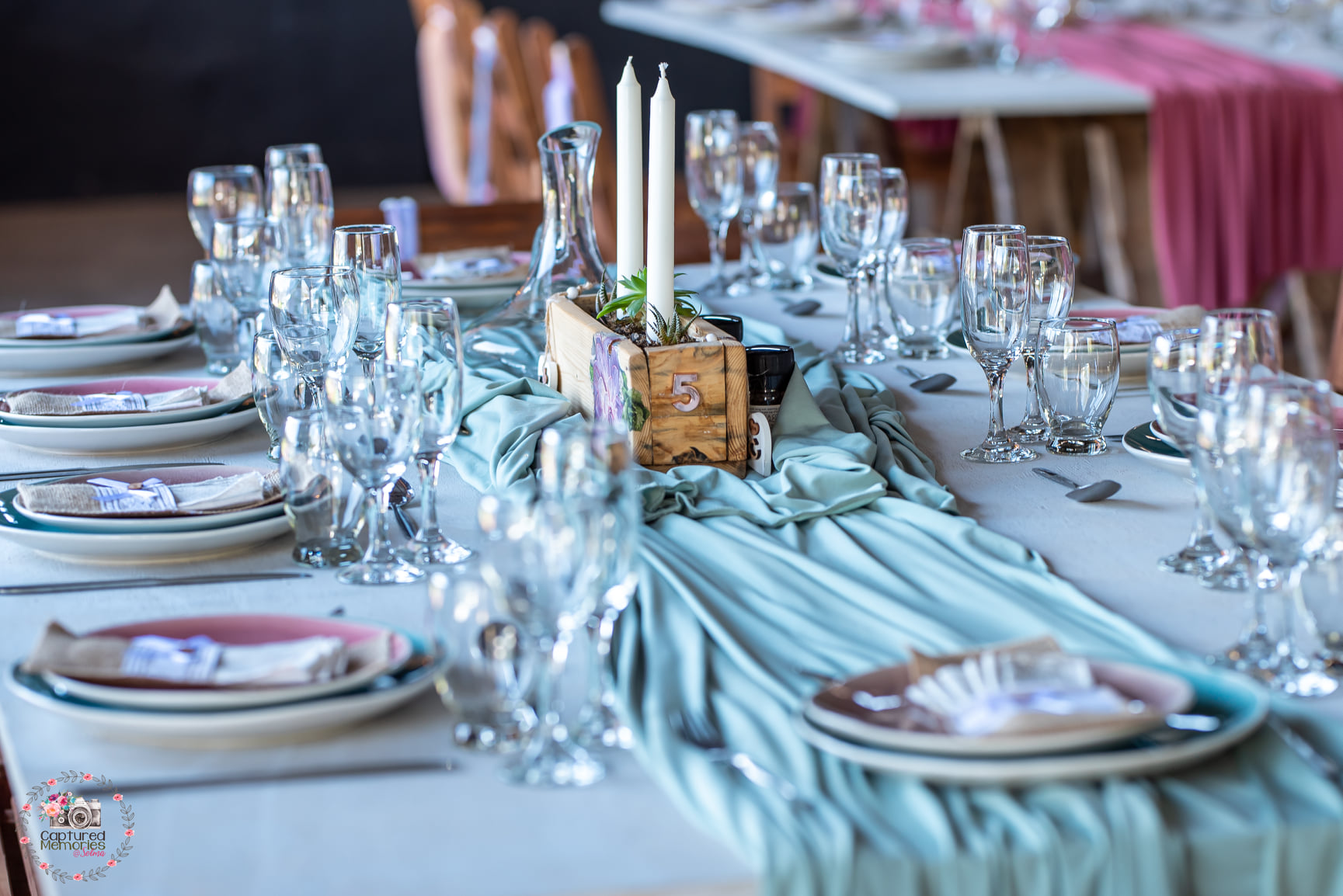 Reception table with a pale green runner, candles and glassware.