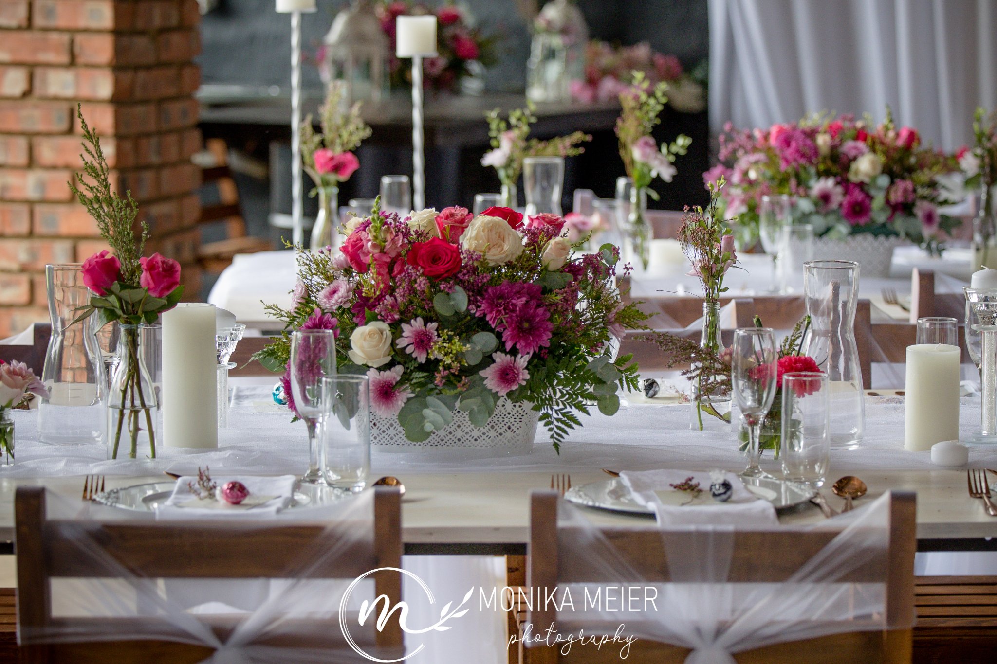 Wedding reception table with pink and white flowers and candles.